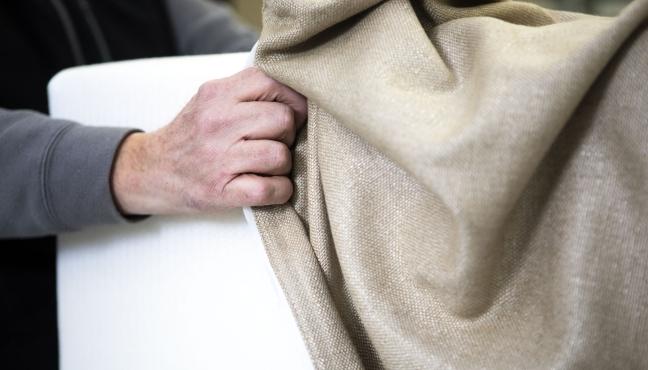 Hands fitting a cover on a sofa cushion