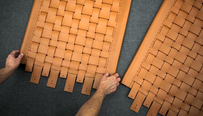 An artisan arranging two pieces of woven leather